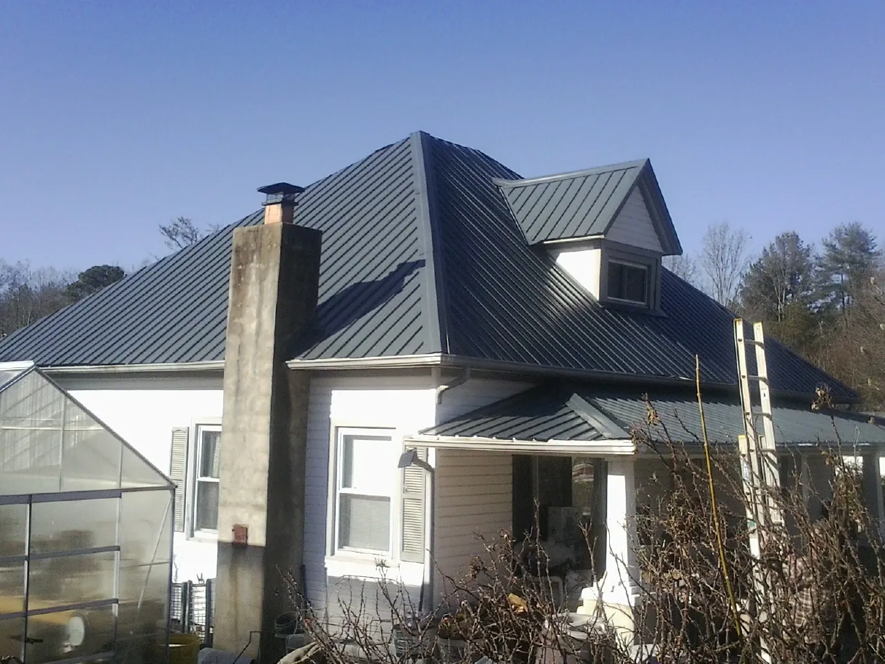 Dark blue standing seam metal roof on a white farmhouse with dormer — Slate & Tile Roof Repair by Roofing Brothers in Canfield