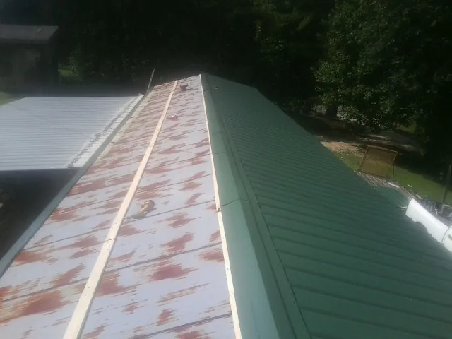 Old rusted panels beside newly installed green metal roofing — Wind Damage Roof Repair by Roofing Brothers in Canfield