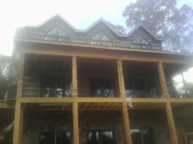 Dormers and porch framing on a large log home under construction — Roof Coating work by our crew in Canfield