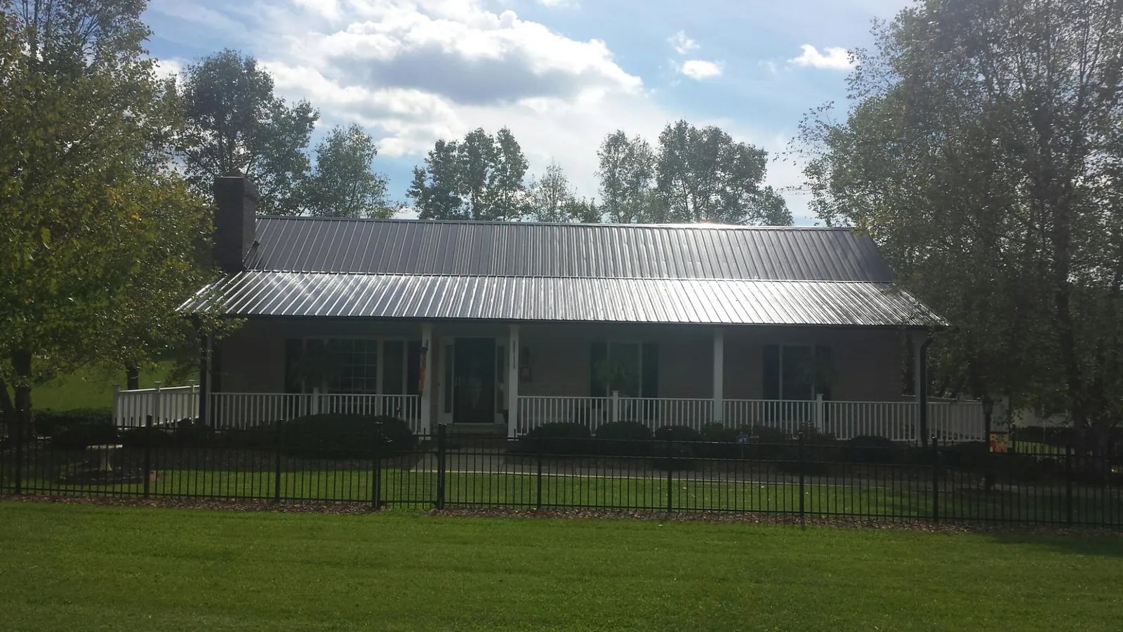 Gray metal roof on a brick ranch with a full width front porch — Gutter Guard Installation work by our crew in Canfield