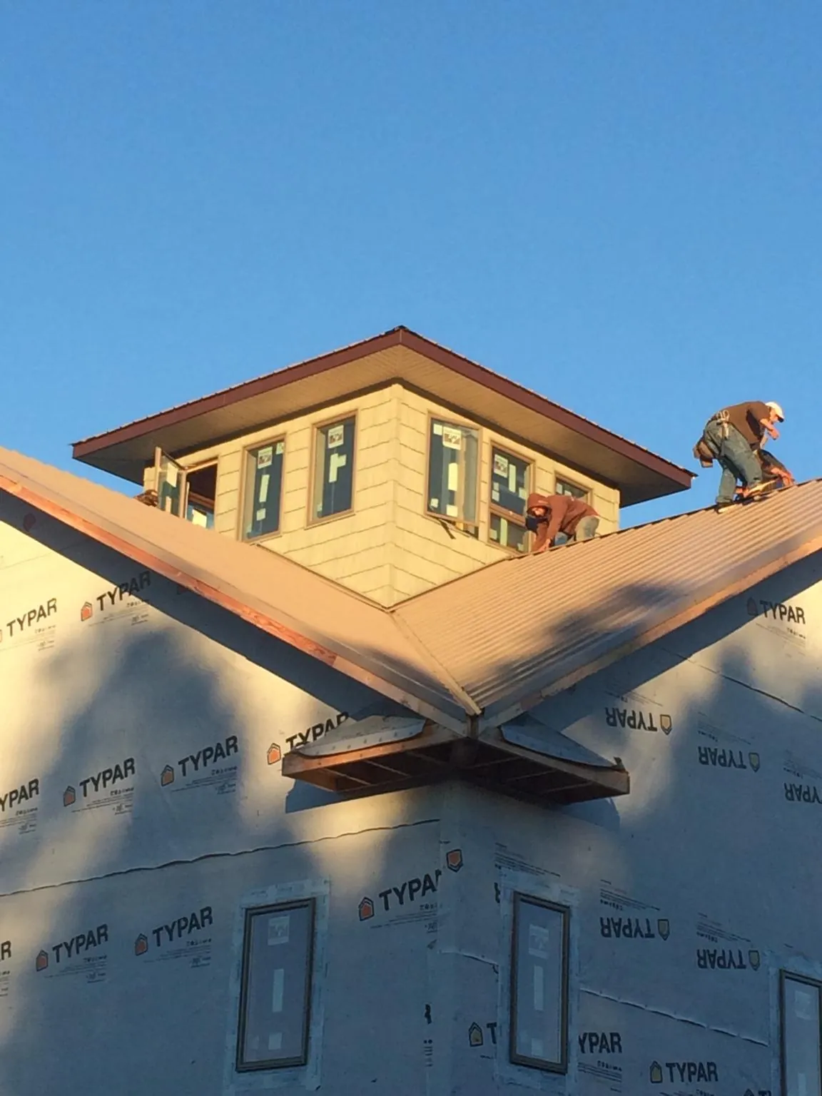 Roofers working around a rooftop cupola on a new metal roof at sunset — Roof Waterproofing in Canfield by Roofing Brothers